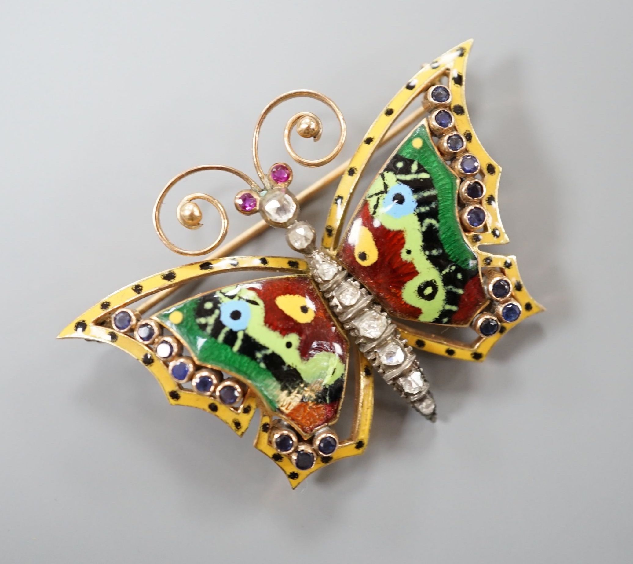 A continental yellow metal, polychrome enamel, rose cut diamond and gem set butterfly brooch (a.f.), width 50mm, gross weight 13.8 grams.